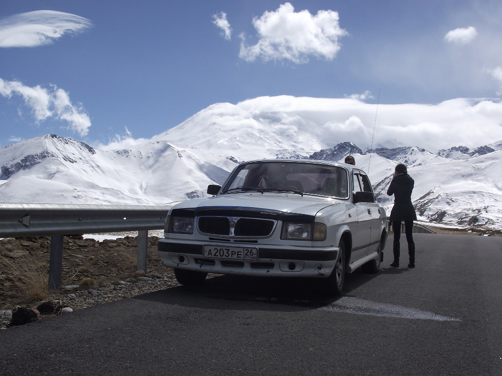 Прямо за машиной, в облаках, высочайшая точка Европы, гора Эльбрус. Навигатор зафиксировал 2390м над уровнем моря.